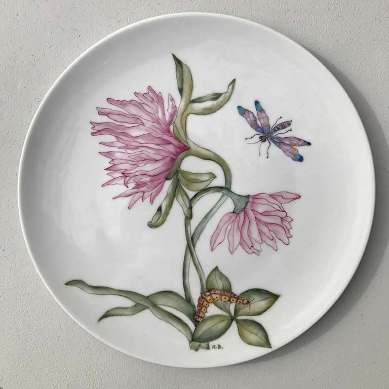 A hand painted porcelain plate with a flower painting on it.