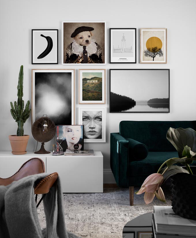 A dark green velvet sofa complemented beautifully by a gallery wall that extends from the sofa's mid length over to a low sideboard's mid length. Image by Desenio.