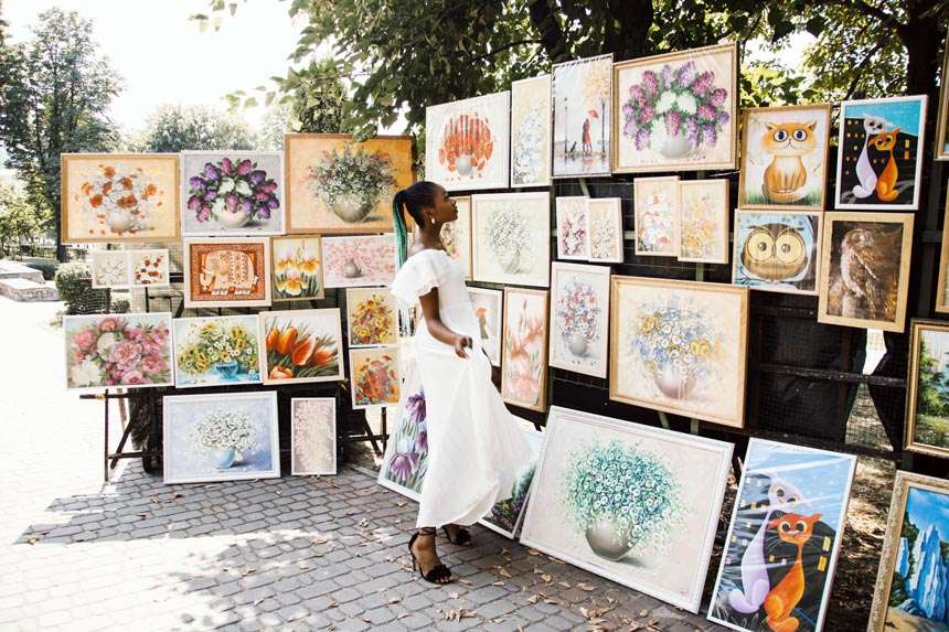 A beautiful black woman looking at some artwork on display somewhere outdoors.