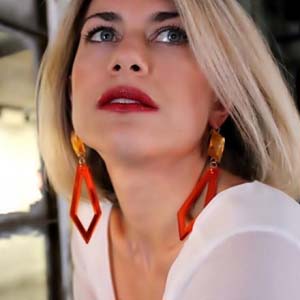 A young blonde woman with long geometric statement earrings