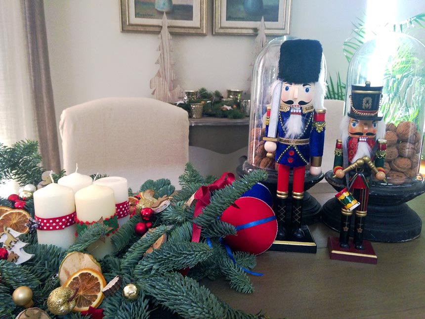 An advent's wreath next to two nutcrackers on a dining table.