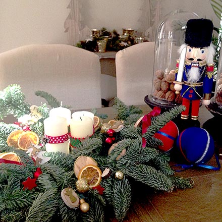 An advent's wreath next to two nutcrackers on a dining table.