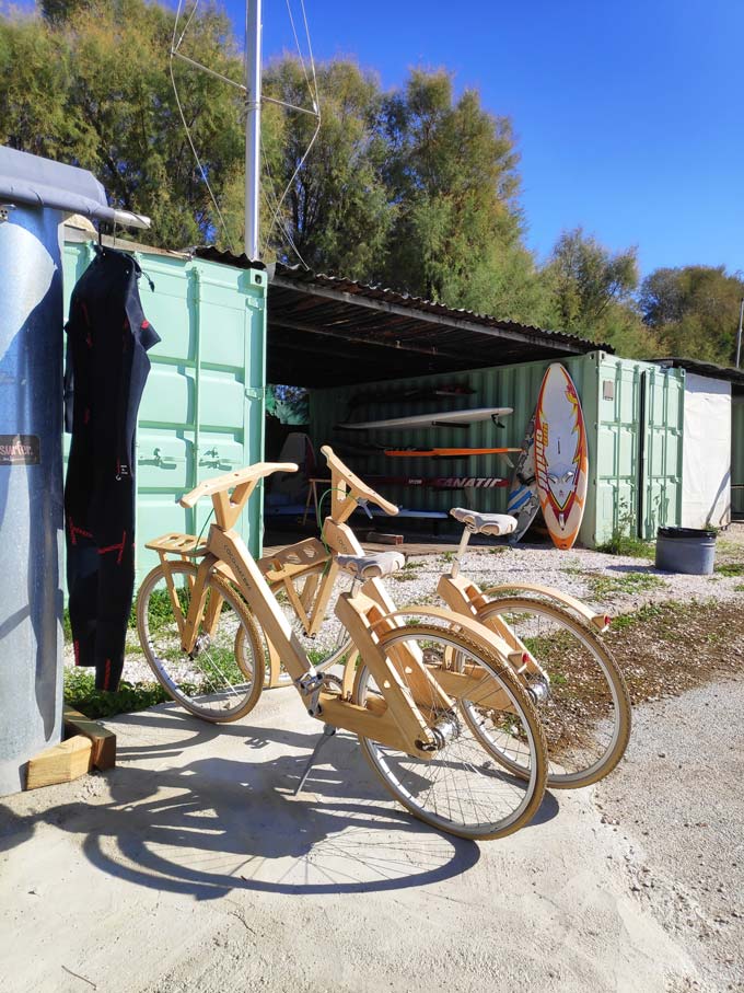Two retro looking bikes parked by a shed where surf boards are stored. Image by Velvet.