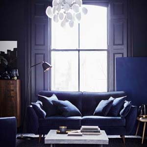 What a cinematic and moody ambiance in this stylish living room, with its blue sofa being flooded by the sunlight from the door window behind. Image from DFS Furniture.