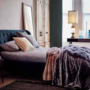 A beautiful bed stand in blue teal and purple bedding and lush throws in a very stylish bedroom with blush pink and teal hues.