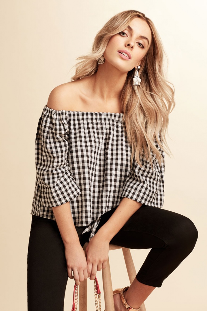 A gingham Bardot top goes nicely with a pair of black pants for a casual look, as worn by the blonde model. Image by Dorothy Perkins.