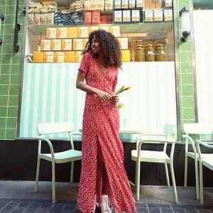 A pretty long red dress with white polka dots worn by a young model with a casual style. Image by Miss Selfridge.