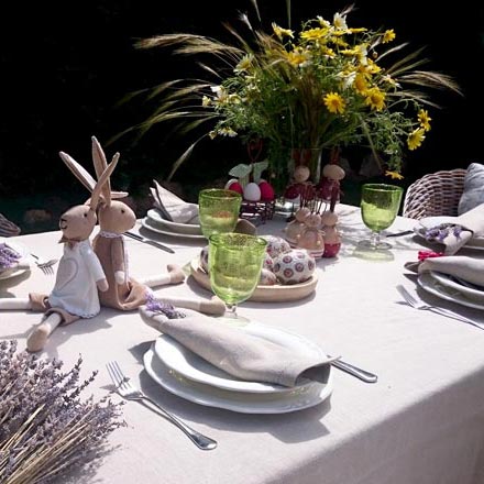 An Easter outdoors table setting with two stuffed bunnies as decor.