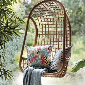 A hanging rattan swing chair creates a great reading nook with a few tropical theme textiles - cocoon perfect! Image by House of Fraser.