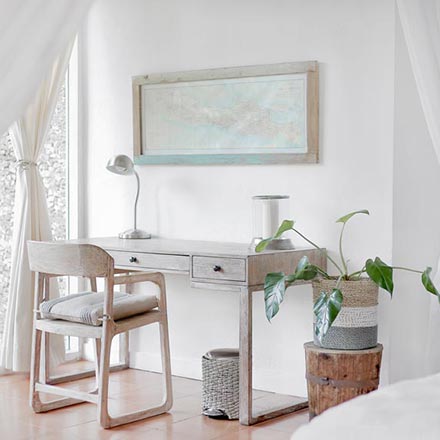 A weathered looking whitewashed desk and chair in an all white room looks as the perfect match. A plant and a whitewashed framed map over the desk ties it all together really nicely.