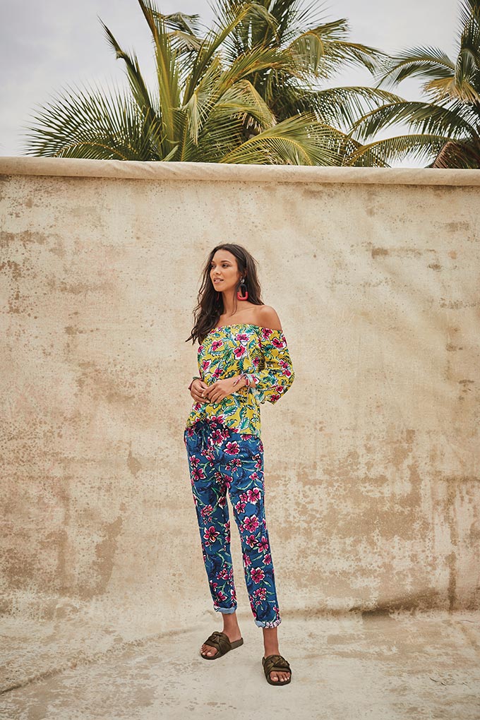 Summer vacation outfit ideas: Who said you can't mix flower patterns? A stylish woman wears a green Bardot top with flower print paired with blue pants and another flower print. Image by Matalan.