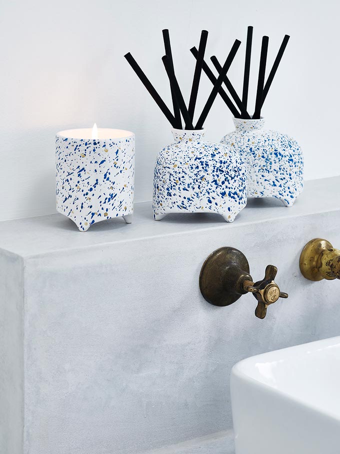 Zen bathroom ideas: A burning candles and two scented stick holders atop a shelf by a sink. Image by Oliver Bonas.
