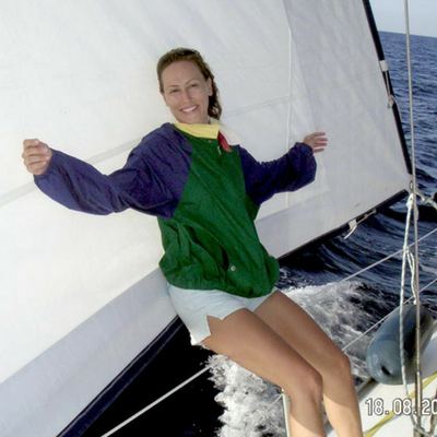 Velvet leaning against an open sail while at cruising with a sailing boat.