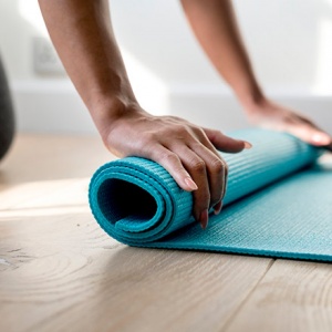 A woman rolling a yoga mat.