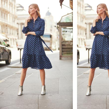 A stylish woman dressed in a blue polka dot dress and silver ankle boots standing in the middle of a street. Image by Sosandar.