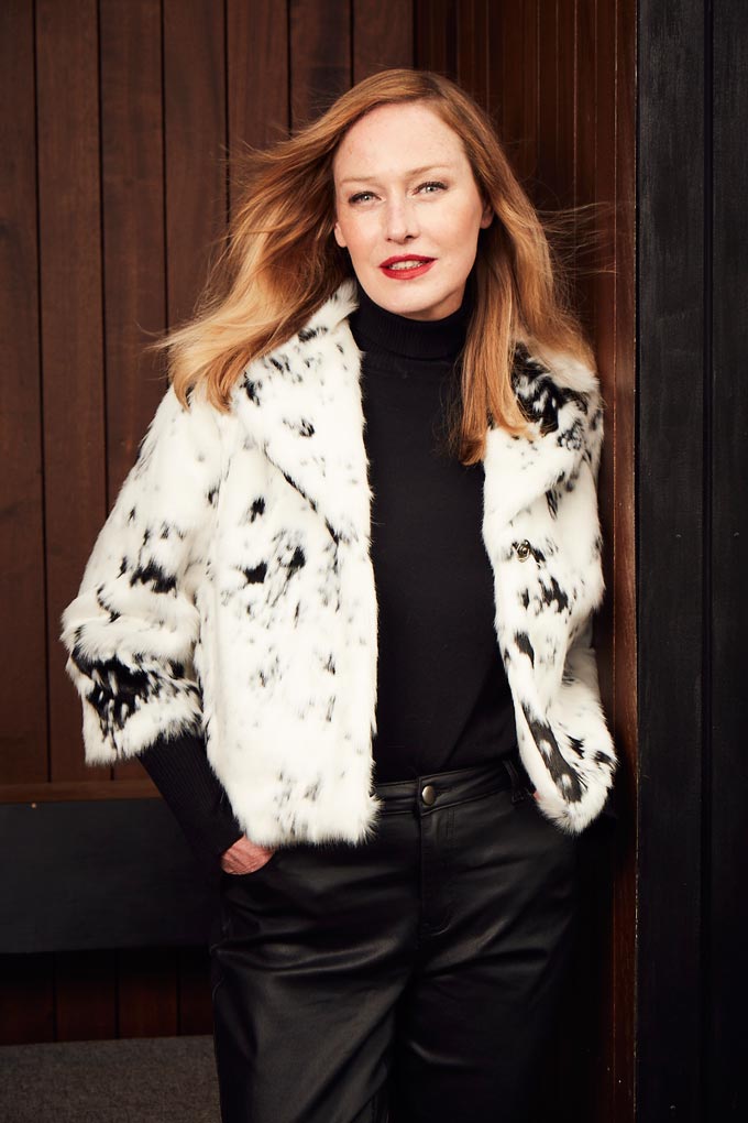A white faux fur jacket with random black spots paired with a black outfit can look stylish and fun - just like this one. Image by JD Williams.
