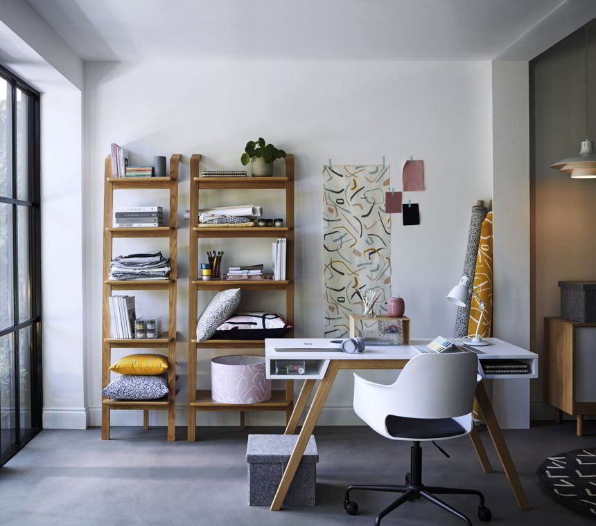 A white space with open shelving and a white desk. A moodboard on the wall insinuates that this must be the work office of some designer. Image by John Lewis.