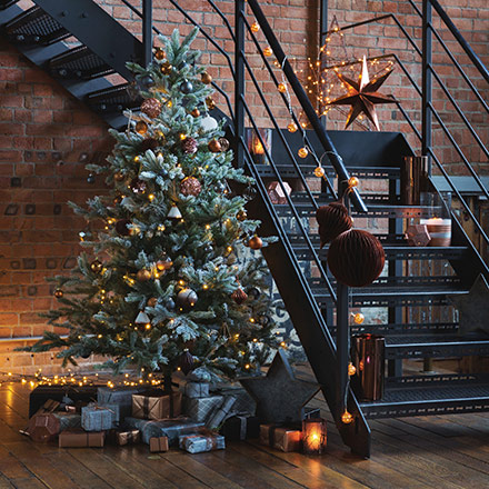 A stunning Christmas tree by a black steel staircase, beautifully decorated. Image by Amara.