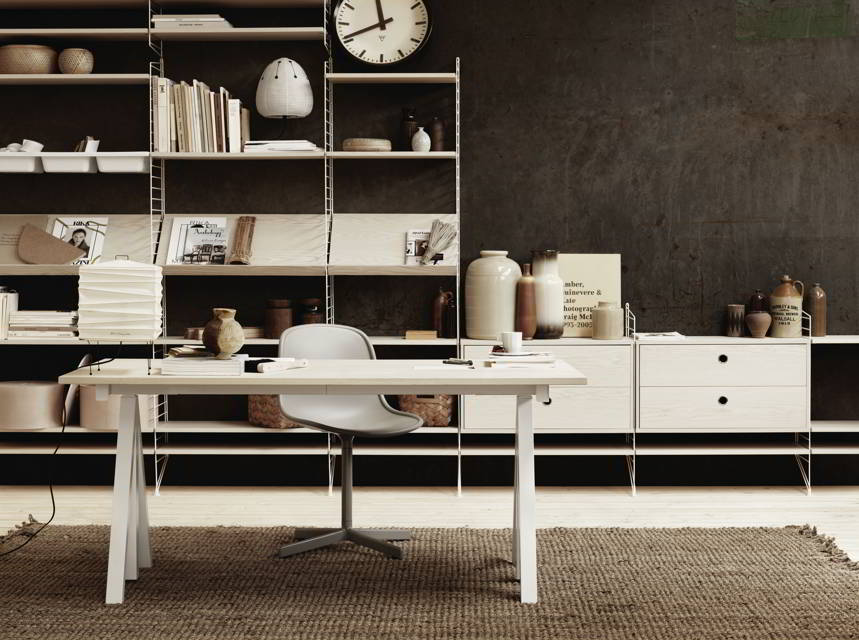 A stylish contemporary office space with a white desk, chair and shelving units in the background against an almost black accent wall. Image by Nest.co.uk.