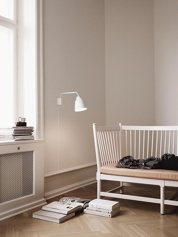 A beige room with a wooden sofa with an accent reading light: Caravaggio Read Wall Light by Lightyears. Image by Nest.co.uk.