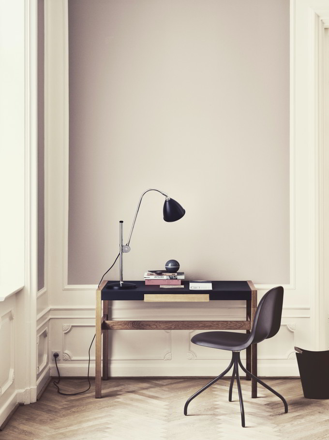 Gubi's BestLite BL1 Table Lamp atop a wooden desk with a black top in a muted color home office space. Image by Nest.co.uk.