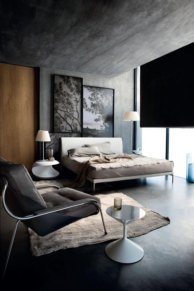 This is a stunning urban chic bedroom with concrete walls, floor and ceiling and large windows from floor to ceiling. The contemporary Zanotta 1883 Talamo bed and armchair complete this minimal setting. Image by Nest.co.uk.