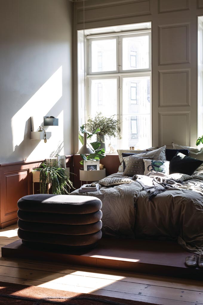 I love this ribbed velvet Ferm Living pouf found in this stylish, warm bedroom with rusty hued panelboards on the walls. Image by Nest.co.uk.