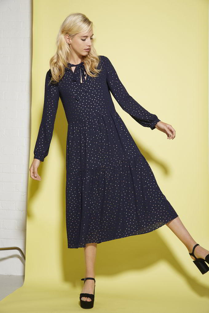 A dark blue dress with polka dots is always a good idea just like this one worn by a blonde woman. Image by Oliver Bonas.