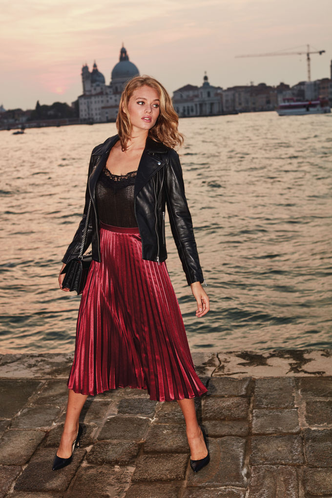 Now this combination is calling my name!! A black leather jacket over a black silk spaghetti strap top paired with a burgundy long pleat skirt and black pumps! Wow! Venice cityscape appears in the background. Image by Sosandar.