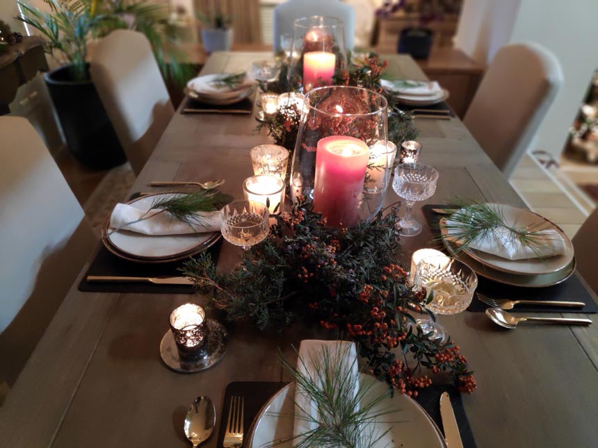 Full view of Elisabeth's Christmas tabletop with two large orange red candles in the middle.