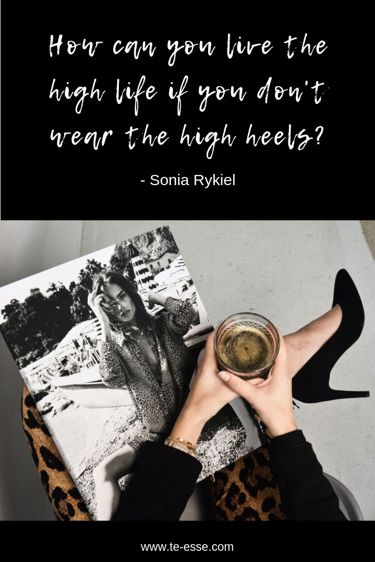 A pin graphic with a quote that reads "how can you live the high life if you don't wear the high heels?" by Sonia Rykiel. The image of a sitting woman wearing a leopard print pair of pants with some black high heels and holding a black and white periodical on her lap compliments the quote. The image is by Cleo Vermij on Unsplash.