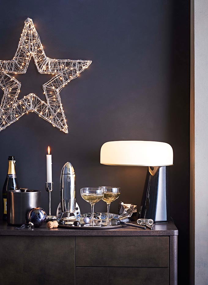 So chic! A moody vignette with a star decor on the midnight blue wall, candlesticks and drinks standing by on the sideboard next to a contemporary table lamp. Image by John Lewis.
