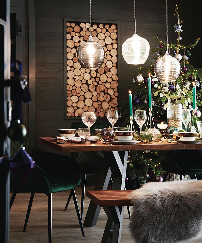 A dark and moody dining space, styled for a festive dinner and a Christmas tree in the background. Simply breathtaking. Image by Next.