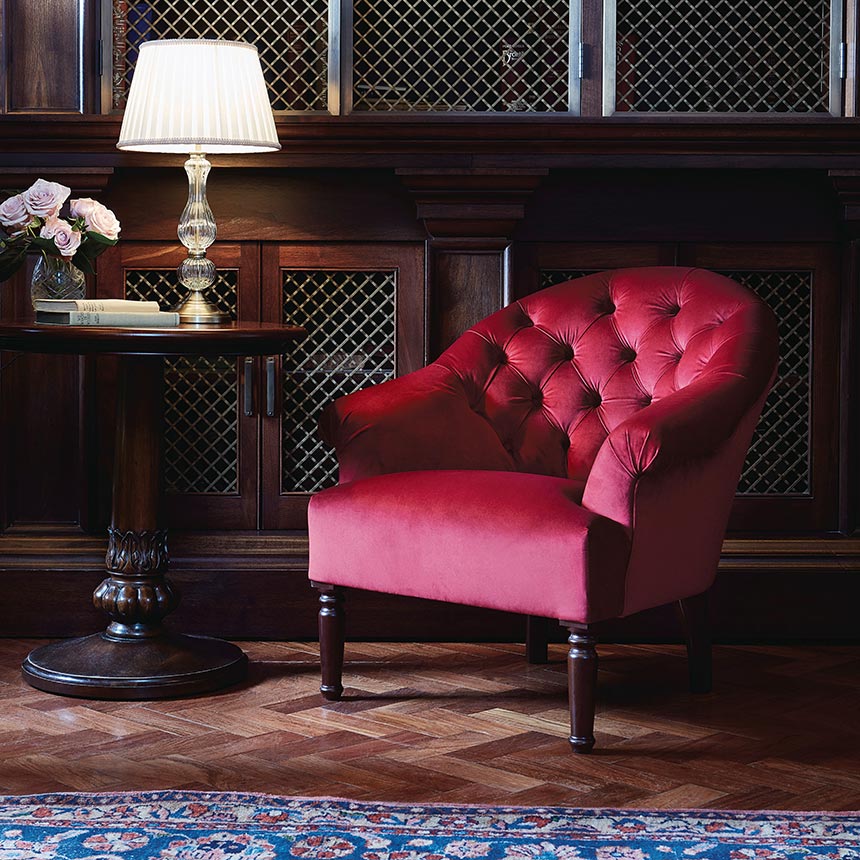 A beautiful vignette with a red velvet armchair, a wooden side table. Lovely! Image by Soho House. 
