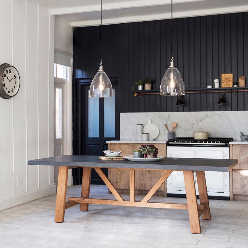 Cement decor ideas: A large dining table with a concrete table top looking real good in this kitchen with a black wall panel wall in the background. The table is from Idyll Home.