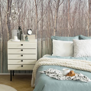 A beautiful bedroom with a wall mural of a forest as an accent and a bed with mint color bedding looking soft and cozy. Image by Pixers.