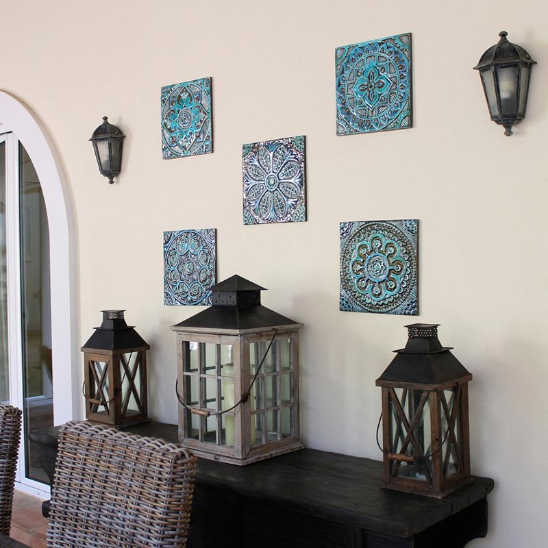 Another wall installation of handmade decorative tiles paired with large rustic lanterns on a dark wood sideboard. Image by G. Vega.