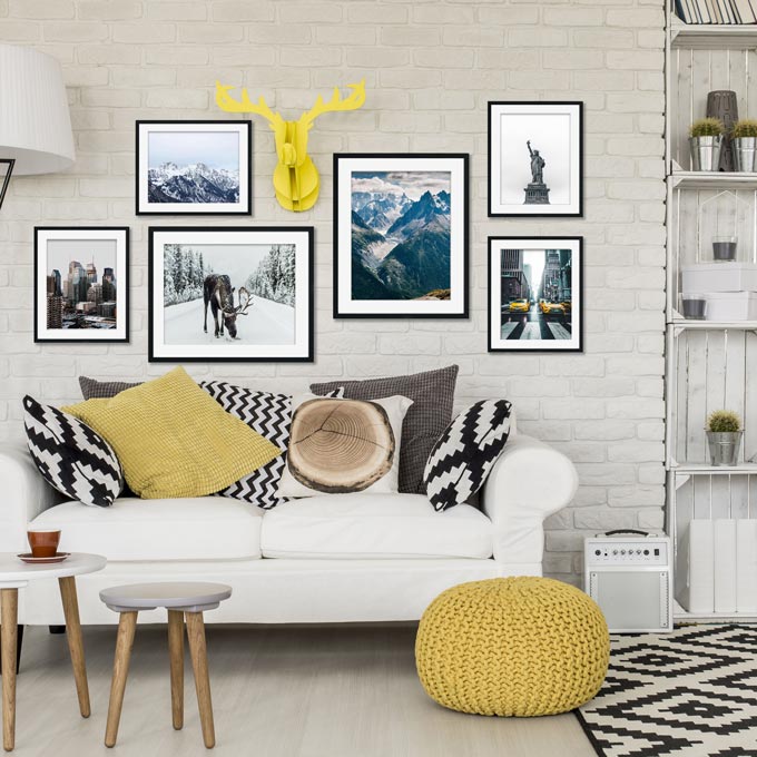 Teen bedroom decorating ideas - wall mural.A contemporary setting with a white sofa, mustard accents, an art gallery wall with prints on a white brick accent wall besides a white bookcase. Image by Abstract House.