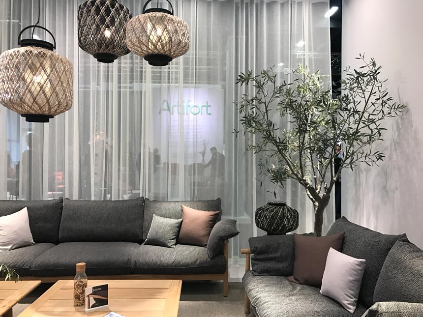 Partial view of a living room with an olive tree between the sofas from the stand of Dedon at imm Cologne 2019.