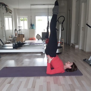 Ifiyenia with her legs up high in a Pilates position.