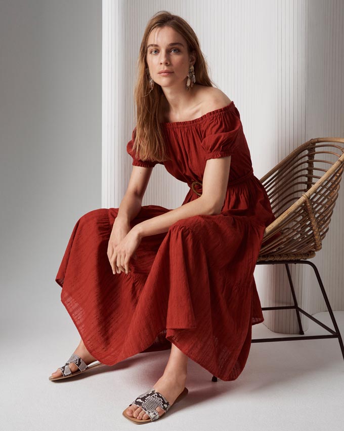 A beautiful off the shoulder maxi dress in a deep terracotta color paired with snake print flat sandals. Image by Marks & Spencer.