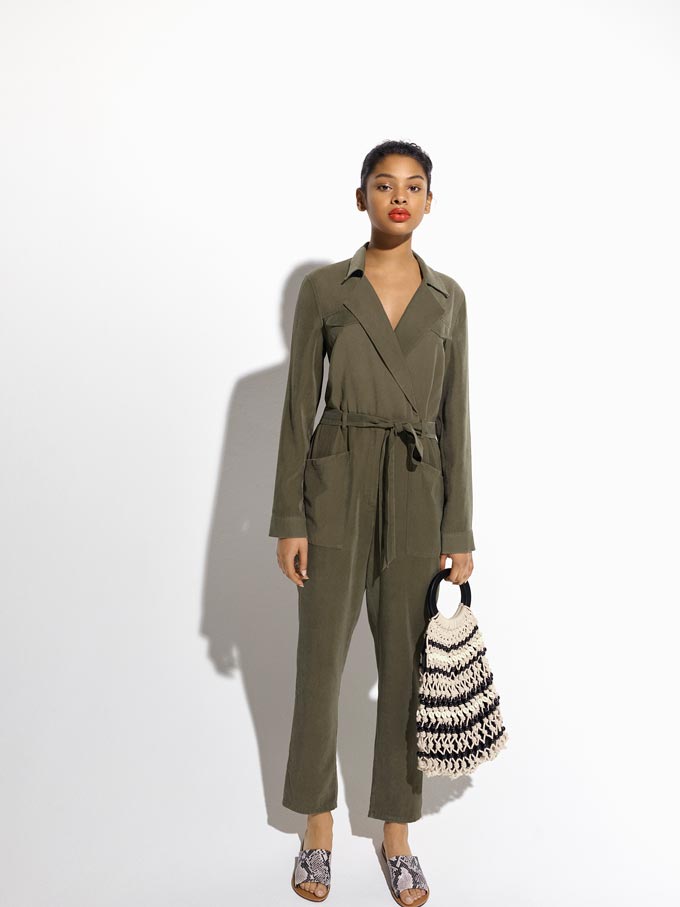 A khaki long sleeve jumpsuit is timeless. In this image it is paired with a striped blue and white straw bag. Image by Miss Selfridge.