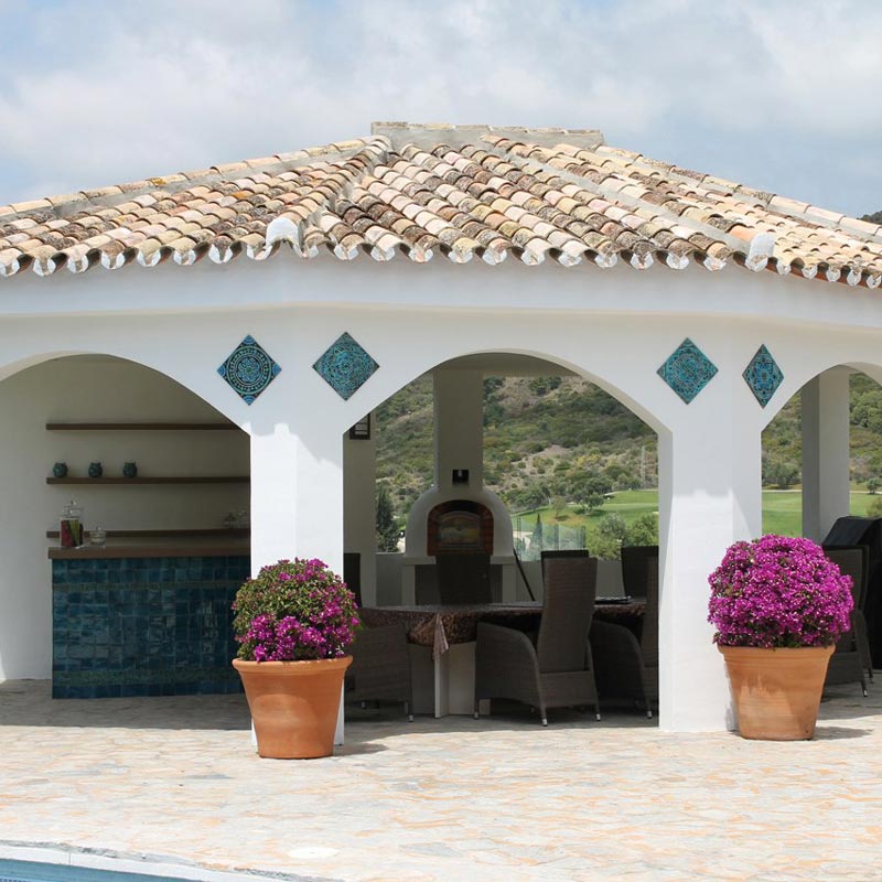 An outdoor BBQ space with a roof and some decorative turquoise handmade tiles that give it an eclectic rustic style. Image by G. Vega.