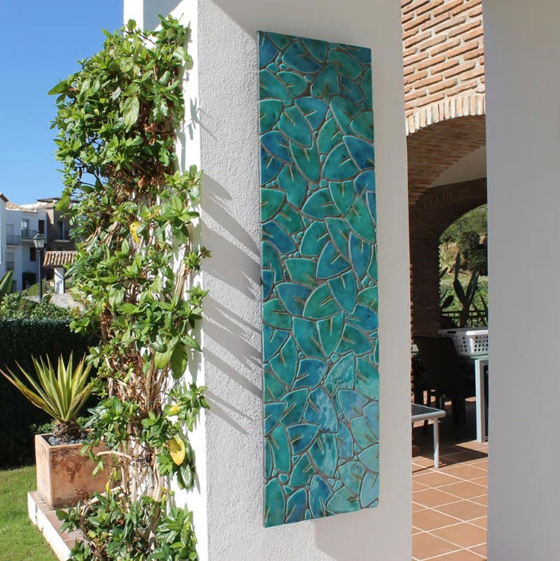 A vertical wall installation made of turquoise tiles on an outdoor house pillar. Image by G. Vega.