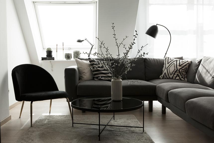A contemporary living room with a modular grey sofa, a round black coffee table and the velvet upholstered Heather lounge chair. Image by Cult Furniture.