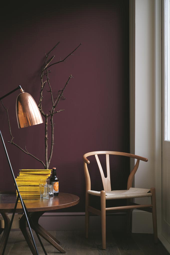 A vignette by a window with an amazing background saturated color on the wall from Farrow and Ball, highlighting a wishbone chair and the round side table perfectly. Image by Farrow and Ball.