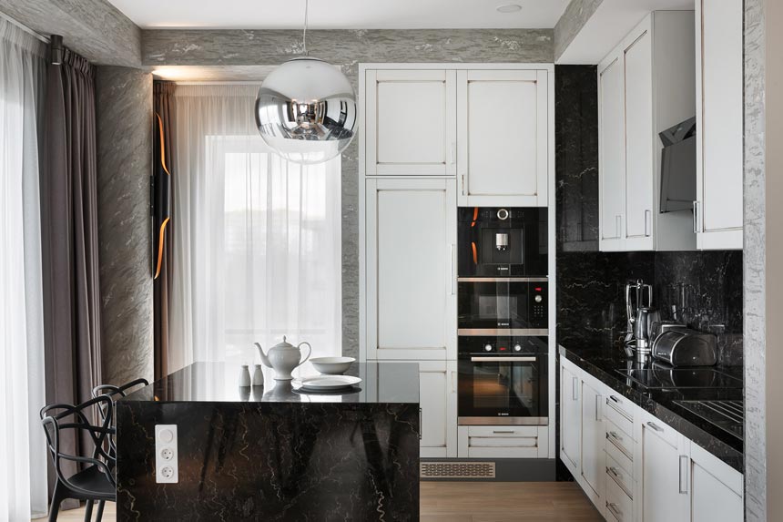 What a beautiful black and white kitchen with a stunning pendant light over the black kitchen island. Image by DelightFULL.