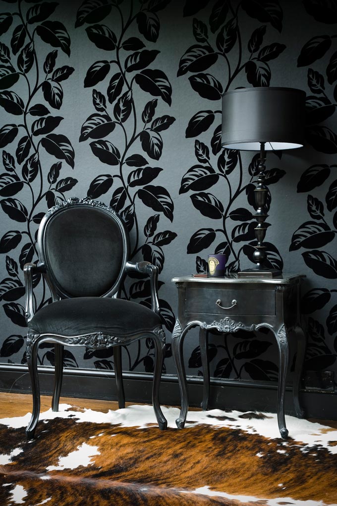 The power of color coordination is definitely overpowering this vignette with sophistication. A graphite gray background with black print leaves on a wallpapered wall act as a backdrop to a graphite grey velvet upholstered vintage inspired armchair and side table in this captivating vignette. Image: The French Bedroom Co. 