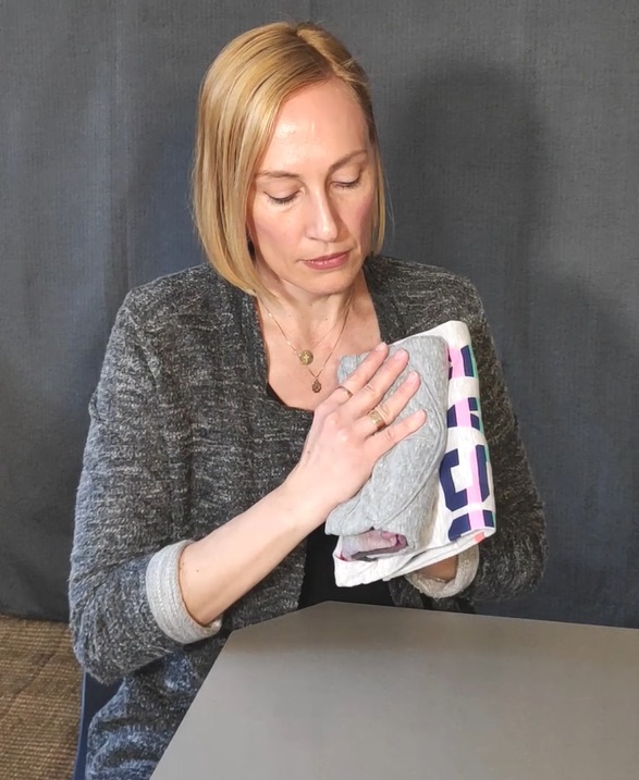 Velvet comparing the different size of two folded tees while organizing a closet as a maximalist.