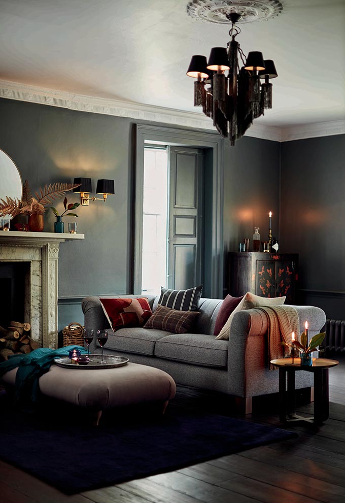 A living room in a deep blue grey saturated hue can look quite warm and inviting when the sofa is right. It's not about the fireplace, but the comfort and homey feeling it emits. Image by DFS. 